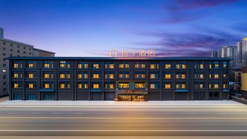 A modern hotel building with multiple floors, large windows, and a prominent neon sign.