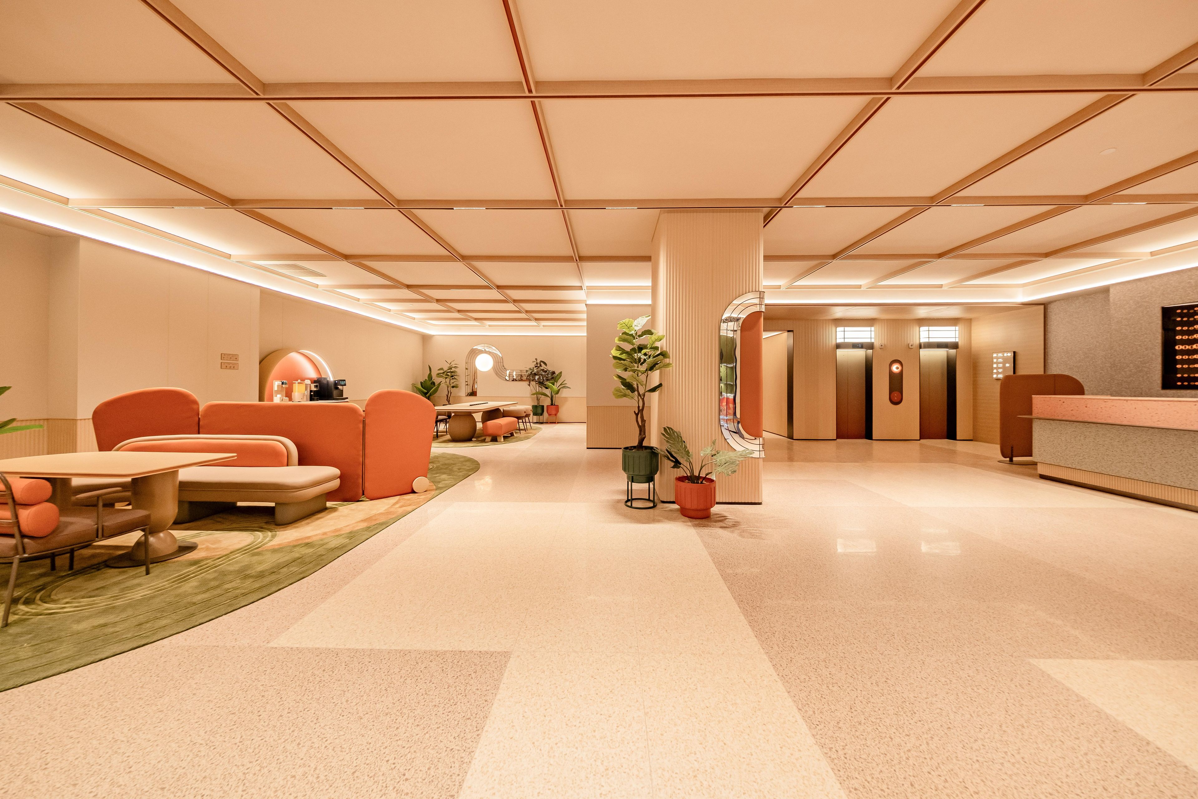 Un vestíbulo de hotel con mostrador de recepción, zona de estar y ascensores.