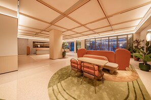 Ein modernes Interieur mit einer Rezeption, einer Sitzgruppe und großen Fenstern.