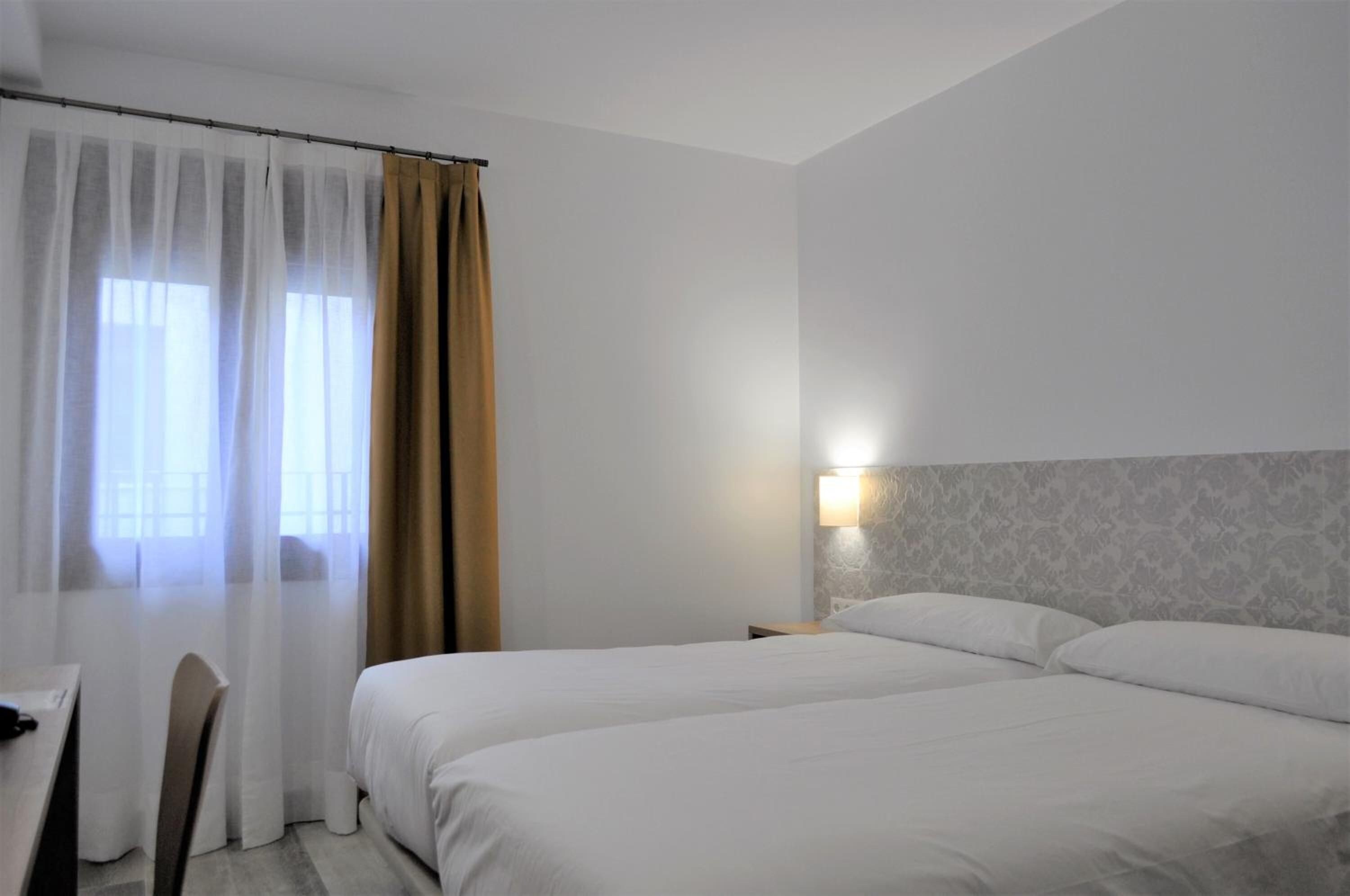 Ein Hotelzimmer mit zwei Betten, einem Schreibtisch und einem Stuhl.