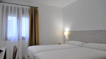 Ein Hotelzimmer mit zwei Betten, einem Schreibtisch und einem Stuhl.
