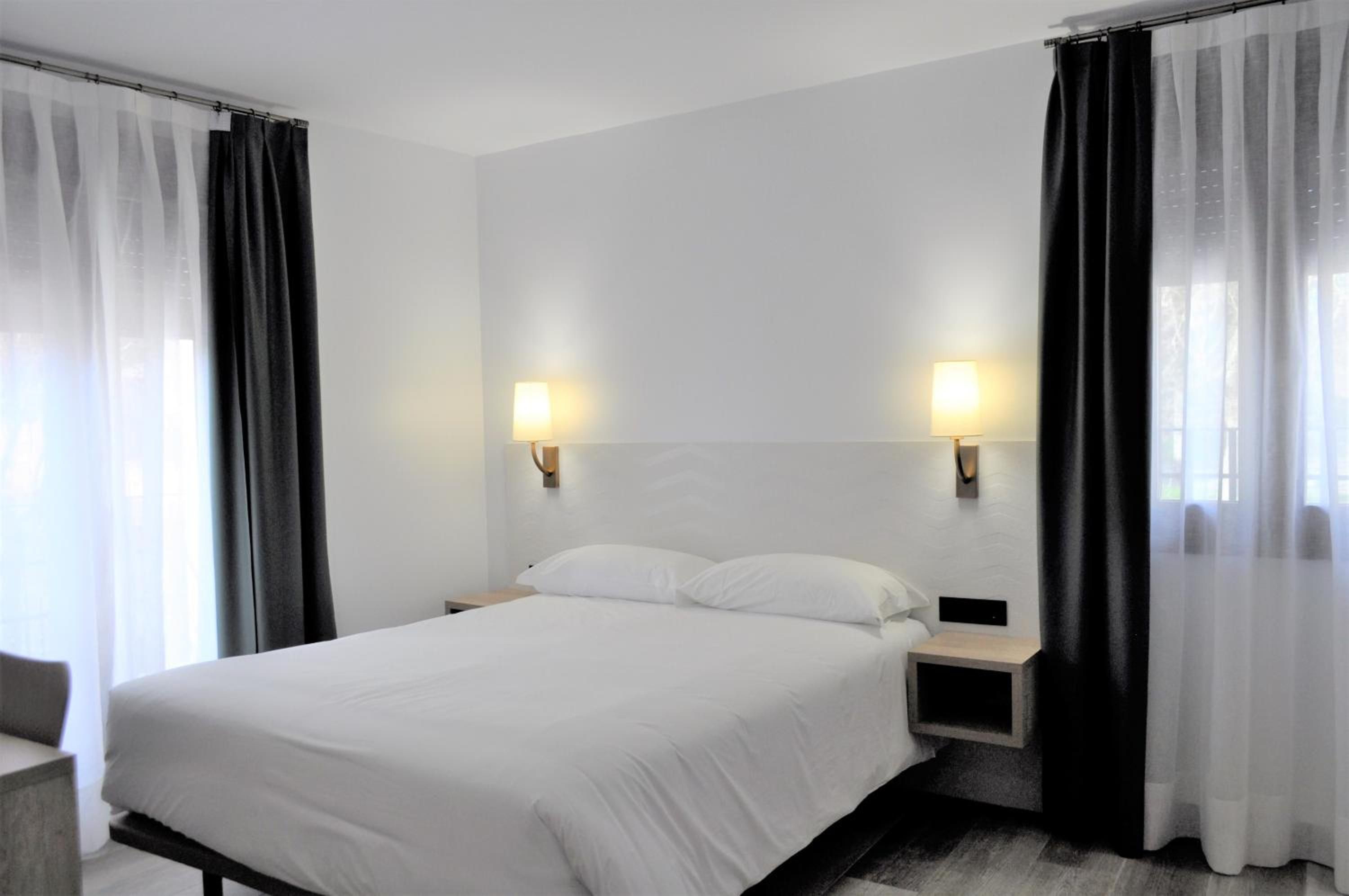Ein Hotelzimmer mit einem Bett, zwei Nachttischen und Vorhängen.