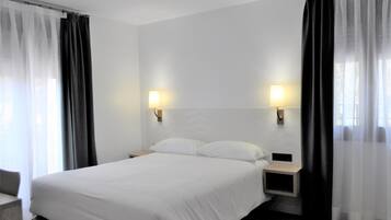 Ein Hotelzimmer mit einem Bett, zwei Nachttischen und Vorhängen.