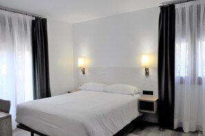 Una habitación de hotel con una cama, dos mesitas de noche y cortinas.