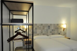 Ein Hotelzimmer mit Etagenbett, Nachttisch, Wandlampe und Wandverkleidung mit Muster.
