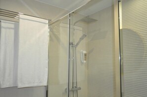 Eine gläserne Duschkabine mit Handbrause und fest installierter Bedienung.