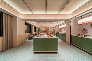 Un hall de hotel con una recepción central, zona de estar y un bufé con diferentes opciones de comida.