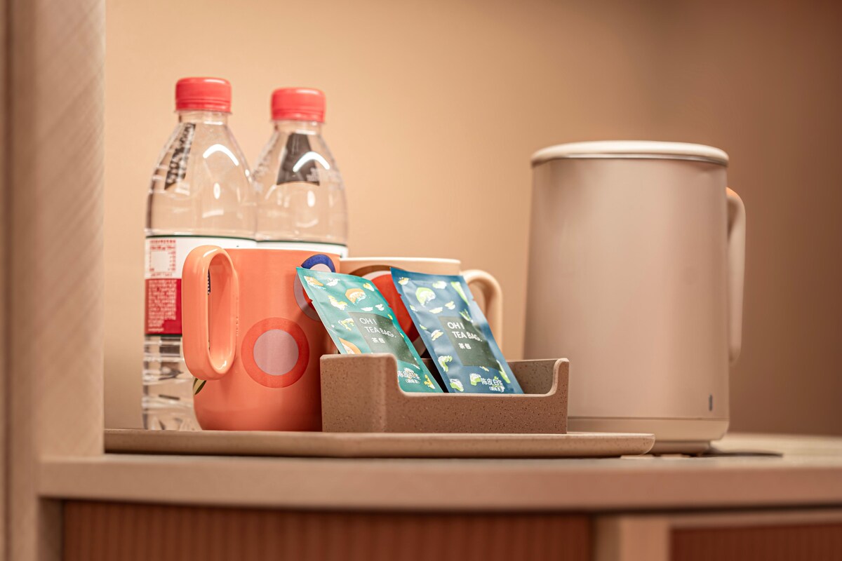 Uma bancada com uma caneca, uma garrafa de água, um termo e um porta-saquinhos de chá.