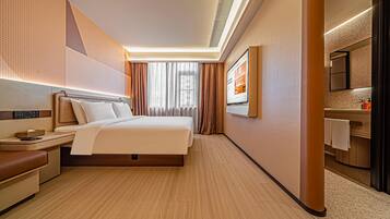 A hotel room with a bed, bedside table, lamp, and a large mirror.