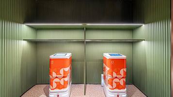 Two orange self-service kiosks in a room with green walls and a speckled floor.