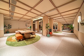 A spacious lobby with a high ceiling, a central seating area with a table and chairs, and potted plants. - Orange Hotel (Xi'an)