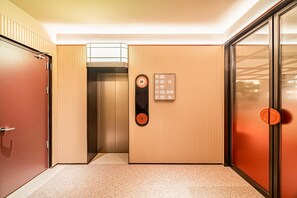 An elevator with a wooden panel design, a control panel with floor selection buttons, and a door with a handle. - Orange Hotel (Xi'an)