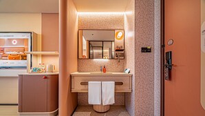 A modern bathroom with a sink, mirror, towel, and a shower area.