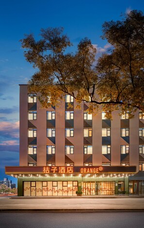 Un hotel moderno con fachada plana, múltiples ventanales y un letrero que dice 'ORANGE'.