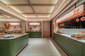 A modern kitchen with a central island, overhead lighting, and a counter displaying kitchen utensils. - Orange Hotel (Xi'an)