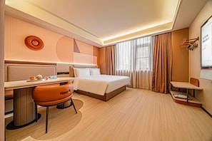 Habitación de hotel con cama, escritorio, silla y vistas al exterior.