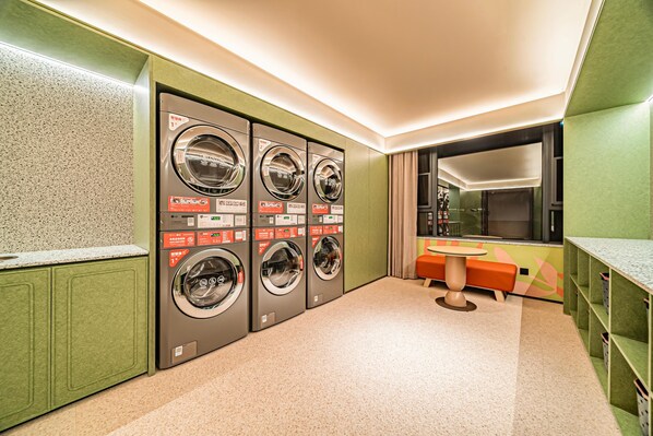 A laundry room with four washing machines, a sink, and a mirror.