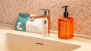A bathroom sink with a chrome faucet and a bottle of hand wash soap. - Orange Hotel (Xi'an)