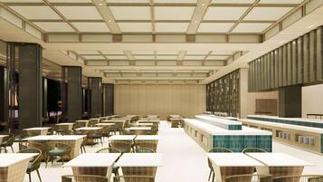 A spacious hotel lobby with high ceilings, a central reception desk, and multiple seating areas with tables and chairs.