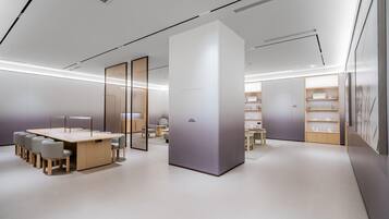 Um interior moderno e minimalista com uma área de estar central, um painel branco grande e uma estante com diversos objetos.