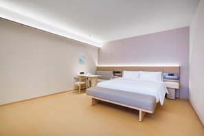Een moderne hotelkamer met een groot bed, nachtkastjes, een bureau en een stoel.