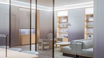 Una habitación moderna y bien iluminada con una zona de estar, una encimera y estantes con diversos objetos.