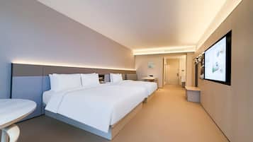 Habitación de hotel con una cama grande, una mesita de noche, televisor montado en la pared y un baño visible a través de una puerta abierta.