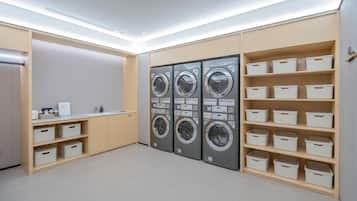 Una sala de lavandería con cuatro lavadoras, contenedores de almacenamiento y un lavabo.