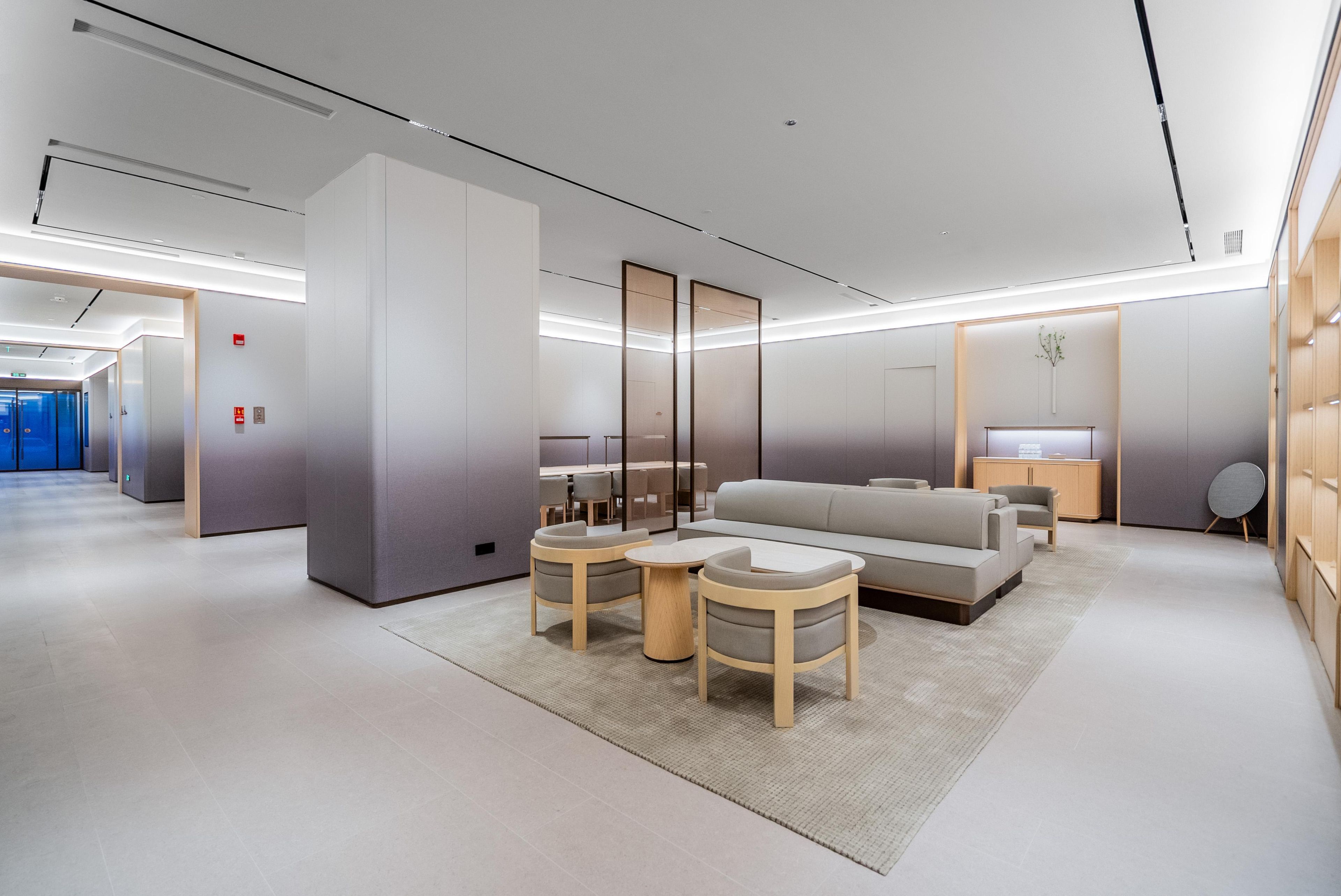 A modern hotel lobby with a sofa, two chairs, a small table, and a mirror.