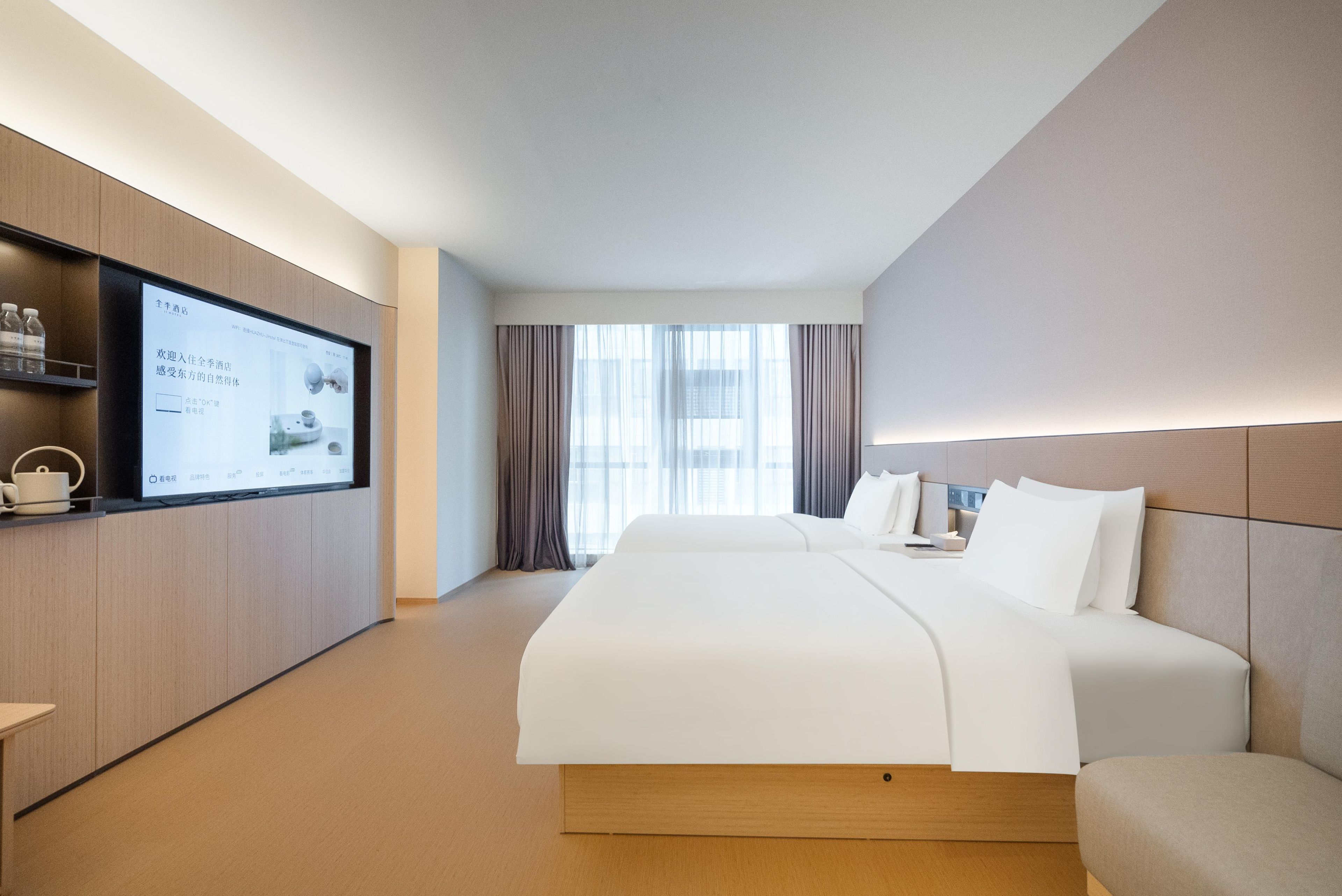 Habitación de hotel con una cama grande, un televisor en la pared y una ventana con cortinas.