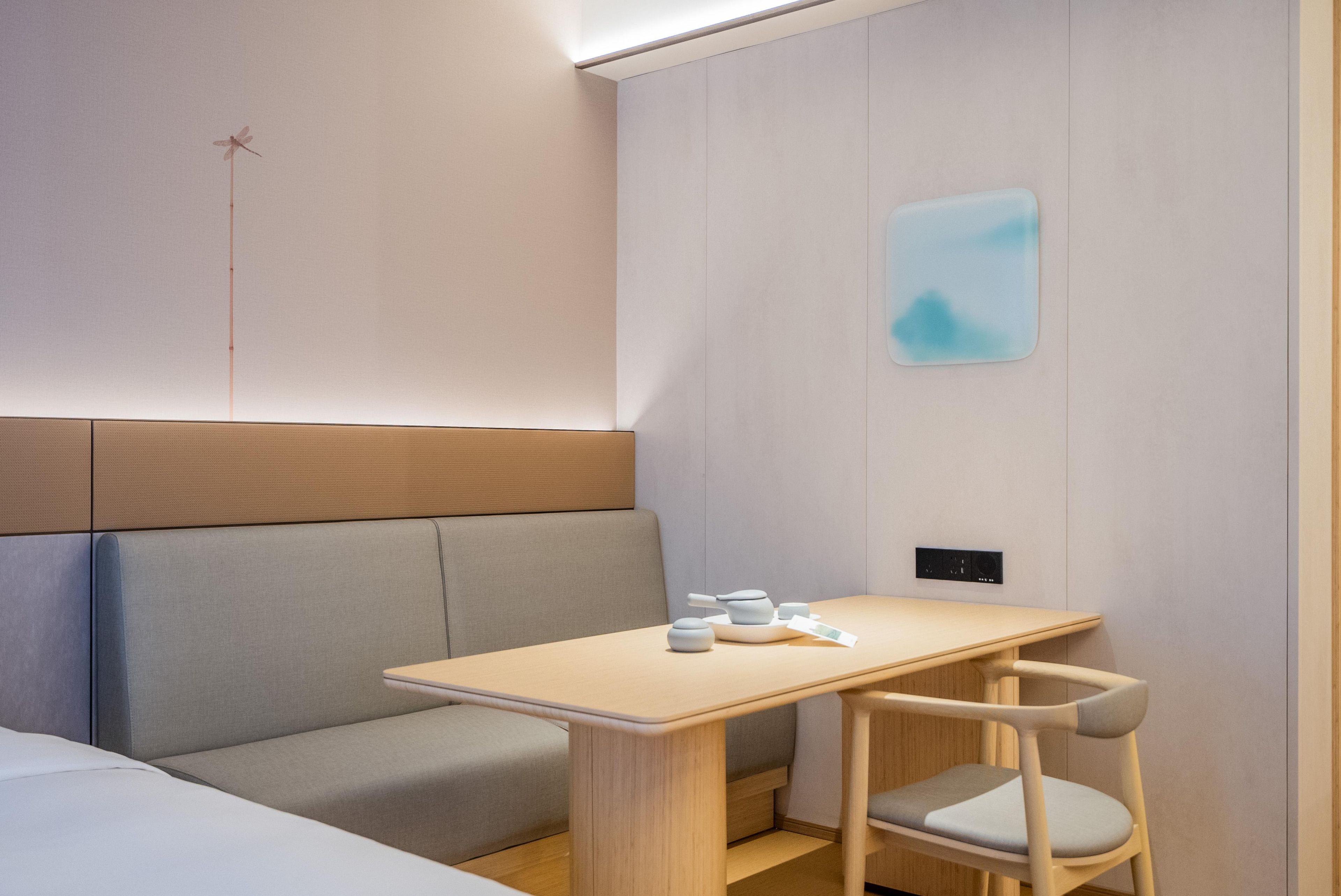 Habitación de hotel moderna con una mesa de madera, un banco acolchado y un diseño minimalista.