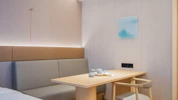 Habitación de hotel moderna con una mesa de madera, un banco acolchado y un diseño minimalista.