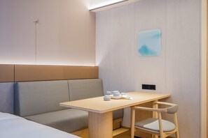 A modern hotel room with a wooden table, a cushioned bench, and a minimalist design. - JI Hotel (Xi'an)