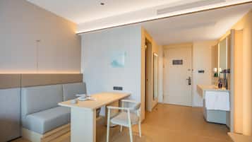Una habitación de hotel moderna con sofá, escritorio, silla, espejo y baño.