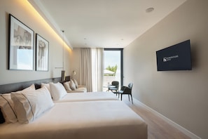 Habitación de hotel con dos camas, televisión y balcón con mobiliario exterior.