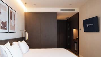Een hotelkamer met een bed, een aan de muur bevestigde televisie en een deur die naar een andere kamer leidt.