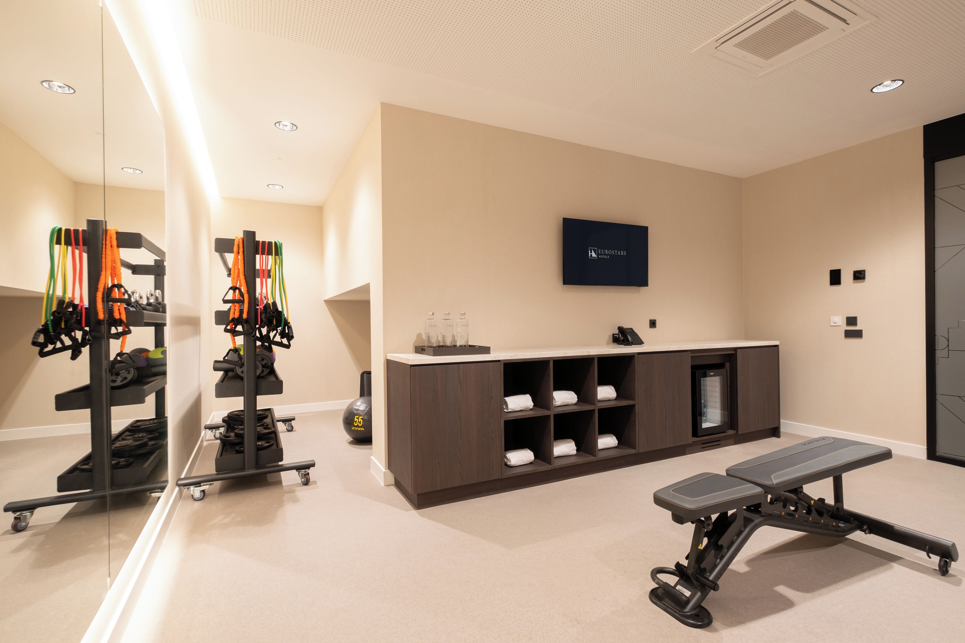 A gym with exercise equipment, a reception desk, and a wall-mounted sign.