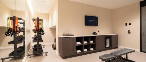 A gym with exercise equipment, a reception desk, and a wall-mounted sign.