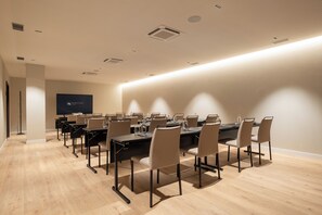 Een vergaderzaal met een lange tafel, stoelen en een projectiescherm.