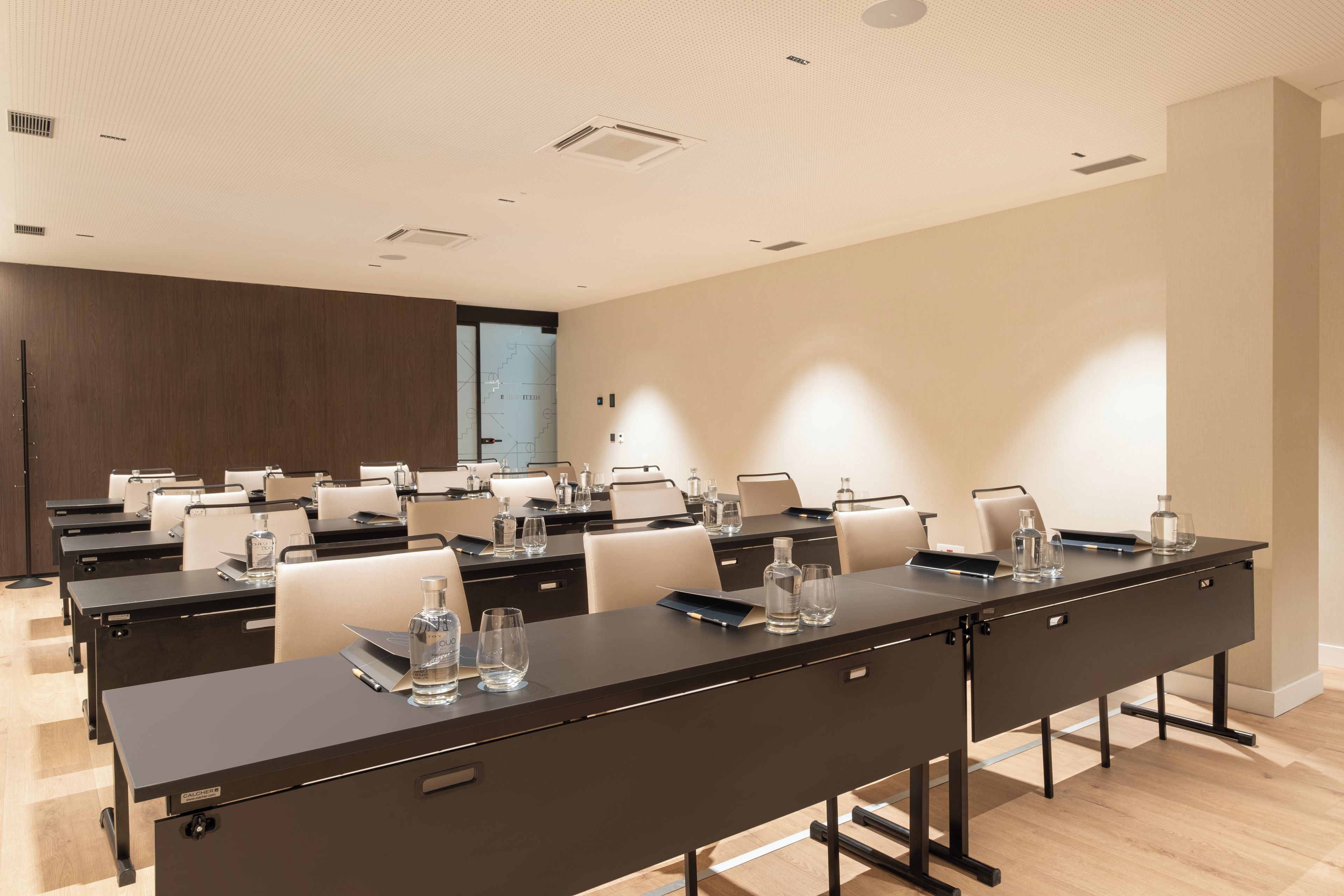 Un salón de conferencias con varias mesas, sillas y botellas de agua.