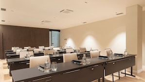 Un salón de conferencias con varias mesas, sillas y botellas de agua.