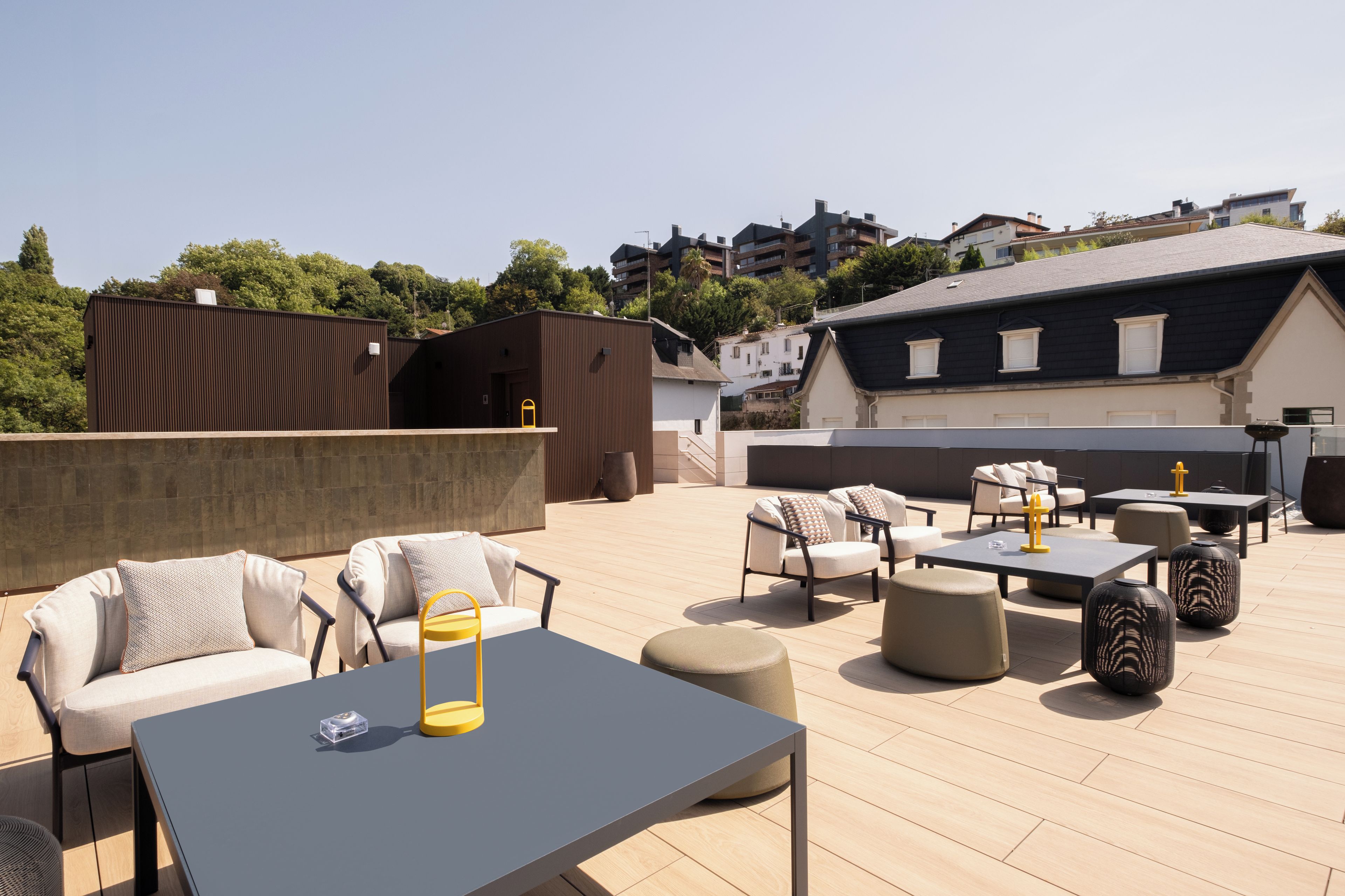 Une terrasse sur le toit, aménagée avec du mobilier d’extérieur, notamment des canapés et des tables, et offrant une vue sur les bâtiments environnants.