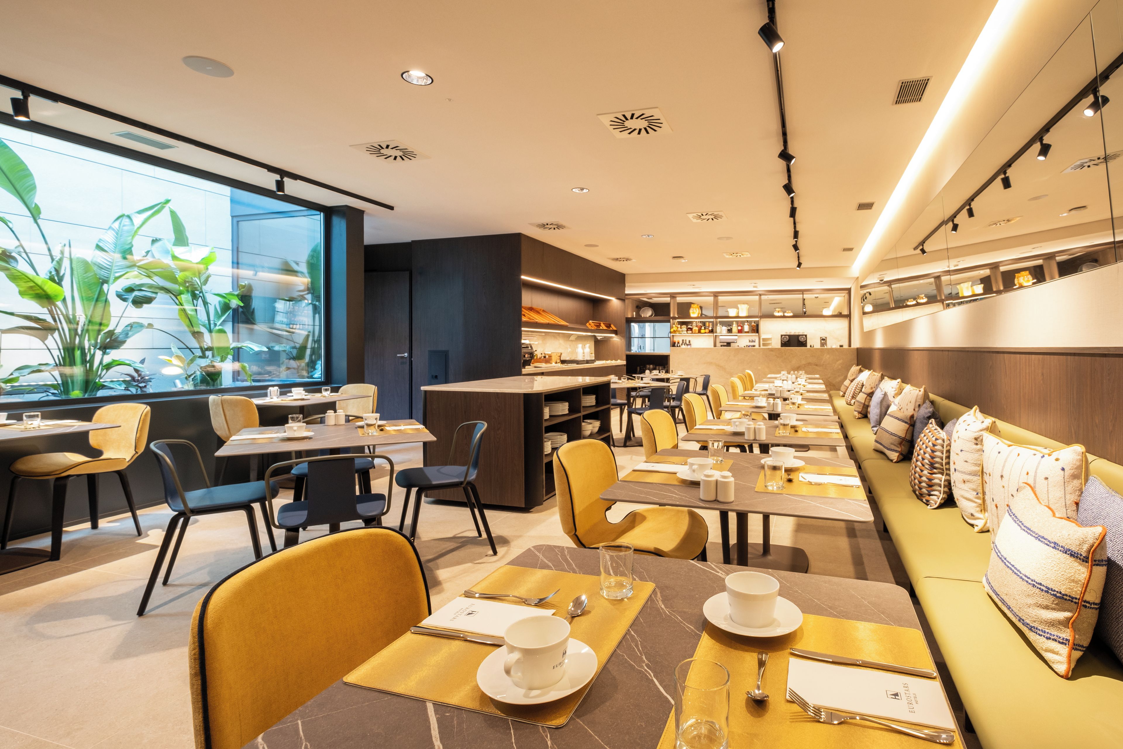 Un restaurante moderno con una amplia zona de comedor común, mesas individuales y una barra.