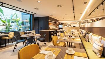 Un restaurante moderno con una amplia zona de comedor común, mesas individuales y una barra.