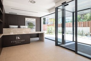 A reception desk with a logo, a modern interior design, and a view of the outdoors. - Eurostars Villa Itziar (San Sebastián)