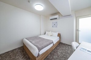 Un dormitorio con cama, escritorio, aire acondicionado y una puerta.