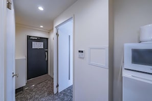 A hallway with a closed door, a thermostat, and a microwave. - Hoshi noYado Imamiya (Osaka)