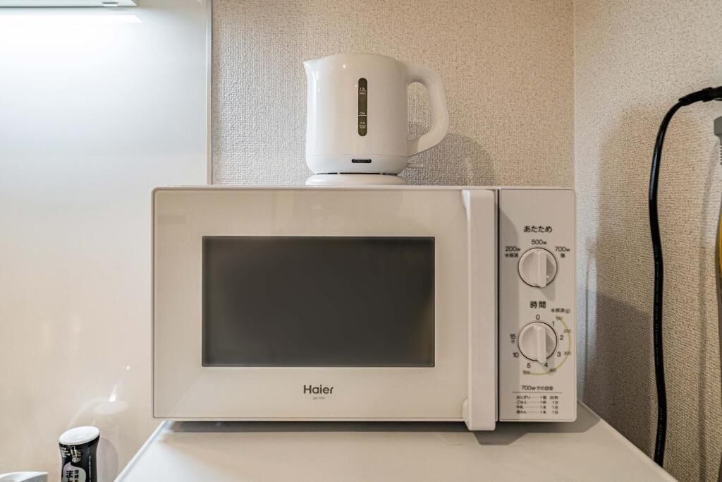 A white Haier microwave oven with a digital display and control panel, placed on a white countertop.