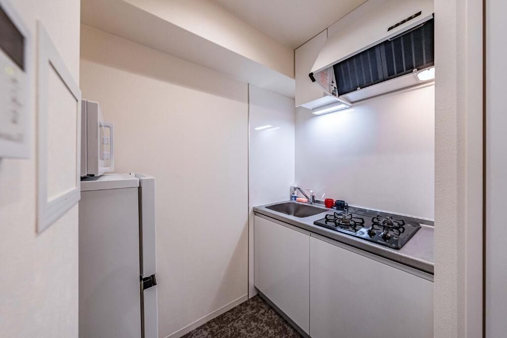 A compact kitchen with a refrigerator, sink, and stove.