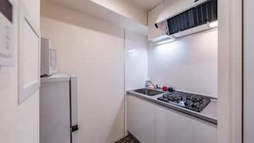 A compact kitchen with a refrigerator, sink, and stove.